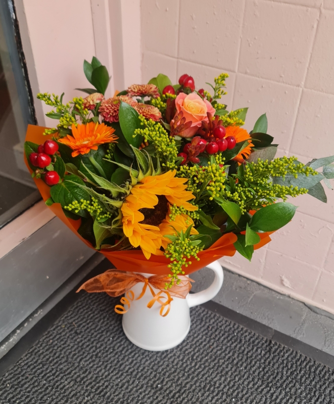 Jug with seasonal hand tied flowers.